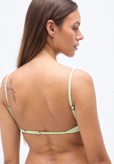 Ανοιχτό πράσινο σουτιέν με ρυθμιζόμενους ιμάντες, λεία υφή και κούμπωμα με αγκράφα στο πίσω μέρος. Μινιμαλιστικός σχεδιασμός με διακριτικές λεπτομέρειες.