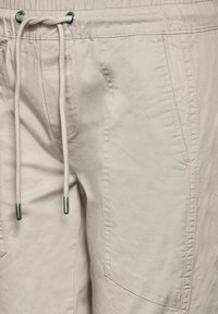 Beiga shorts i lättviktigt tyg med elastisk midja, utrustade med dragsko och sidofickor. Slät, strukturerad yta.