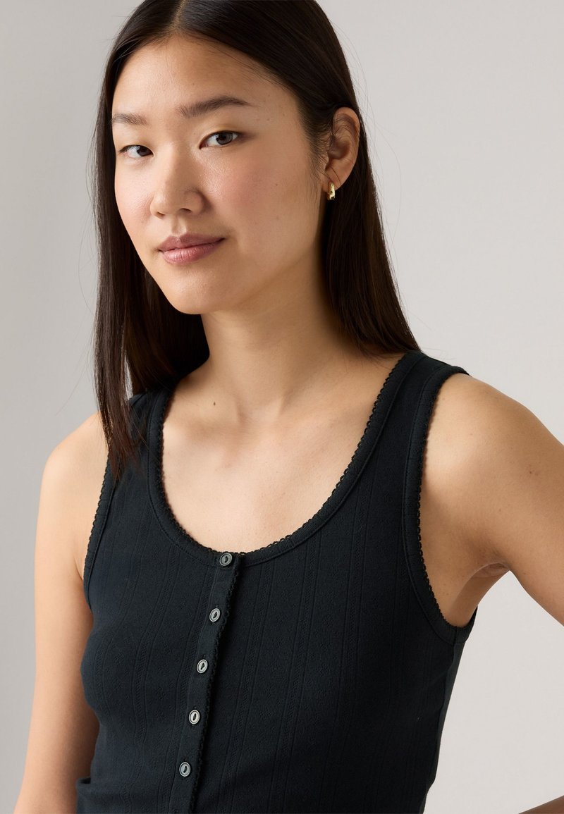 Schwarzes Tanktop mit gerippter Textur, gerundetem Ausschnitt und dekorativem Knopfverschluss vorne. Subtile Wellenkanten.
