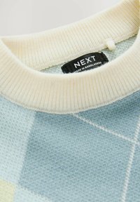 Pull léger bleu avec un tricot texturé, un col côtelé crème et une étiquette de marque noire avec du texte blanc.