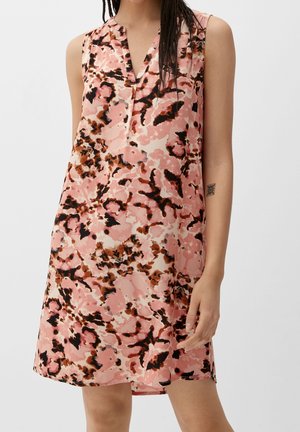 Robe ample sans manches avec motif floral abstrait rose, marron et noir portée par une personne avec des tresses et un tatouage au bras.
