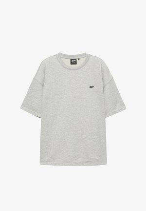 Lysegrå T-shirt med korte ærmer og rund hals med lille sort tekstlogo på venstre bryst og ribstrikket krave.