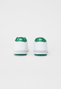 Sneaker bianche con dettagli verdi sul tallone, dotate di una suola in gomma testurizzata e un logo distintivo sul retro. Design semplice con forma arrotondata.