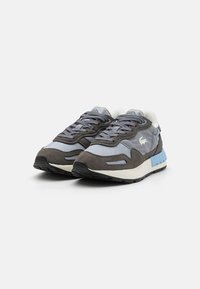 Gray and blue sneakers with a mix of suede and textile materials, featuring a padded collar, lace-up closure, and a textured rubber sole.