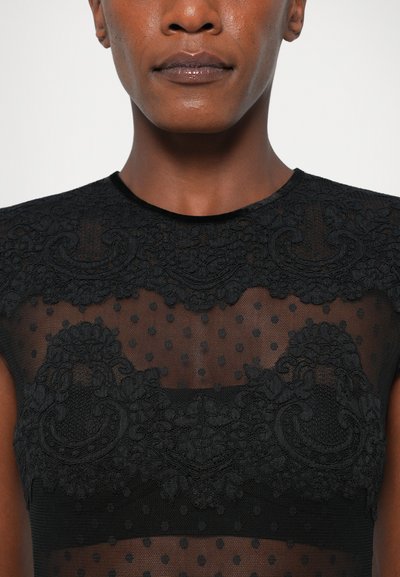 Črna prosojna bluzica z vezenimi cvetličnimi detajli in pikčasto teksturo, s prilegajočim krojem in visokim ovratnikom.