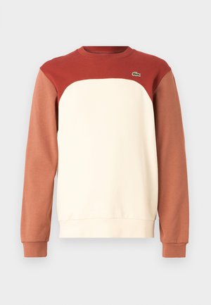 Ronde hals sweatshirt met een rood bovenstuk, een crèmekleurig middenstuk en bruine ondermouwen. Gemaakt van zacht materiaal met een klein logo-detail.