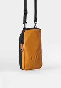 Kompakte orange Umhängetasche mit schwarzen Akzenten, aus glattem Material, mit Reißverschluss und geprägtem Logodetail.
