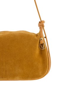 Sac à main en suède jaune moutarde avec une texture lisse, présentant une forme incurvée, une bandoulière détachable et des accents en métal doré.