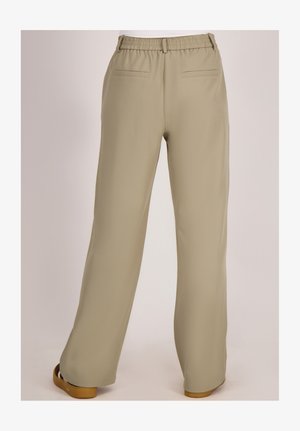 Beige wijde broek met elastische tailleband en paspelzakken, gedragen met bruine platte schoenen, gezien van achteren op een neutrale achtergrond.