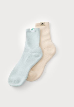 Világoskék és bézs zoknik, bordás mintázattal, középhosszú, puha tapintású, márkás címkékkel, kontrasztos színekkel ellátott logóval.