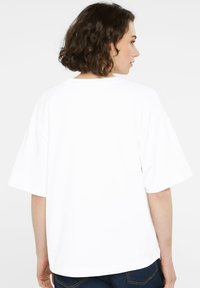 White oversized t-shirt featuring short sleeves, a relaxed fit, and a round neckline, made from soft cotton material with a smooth texture.