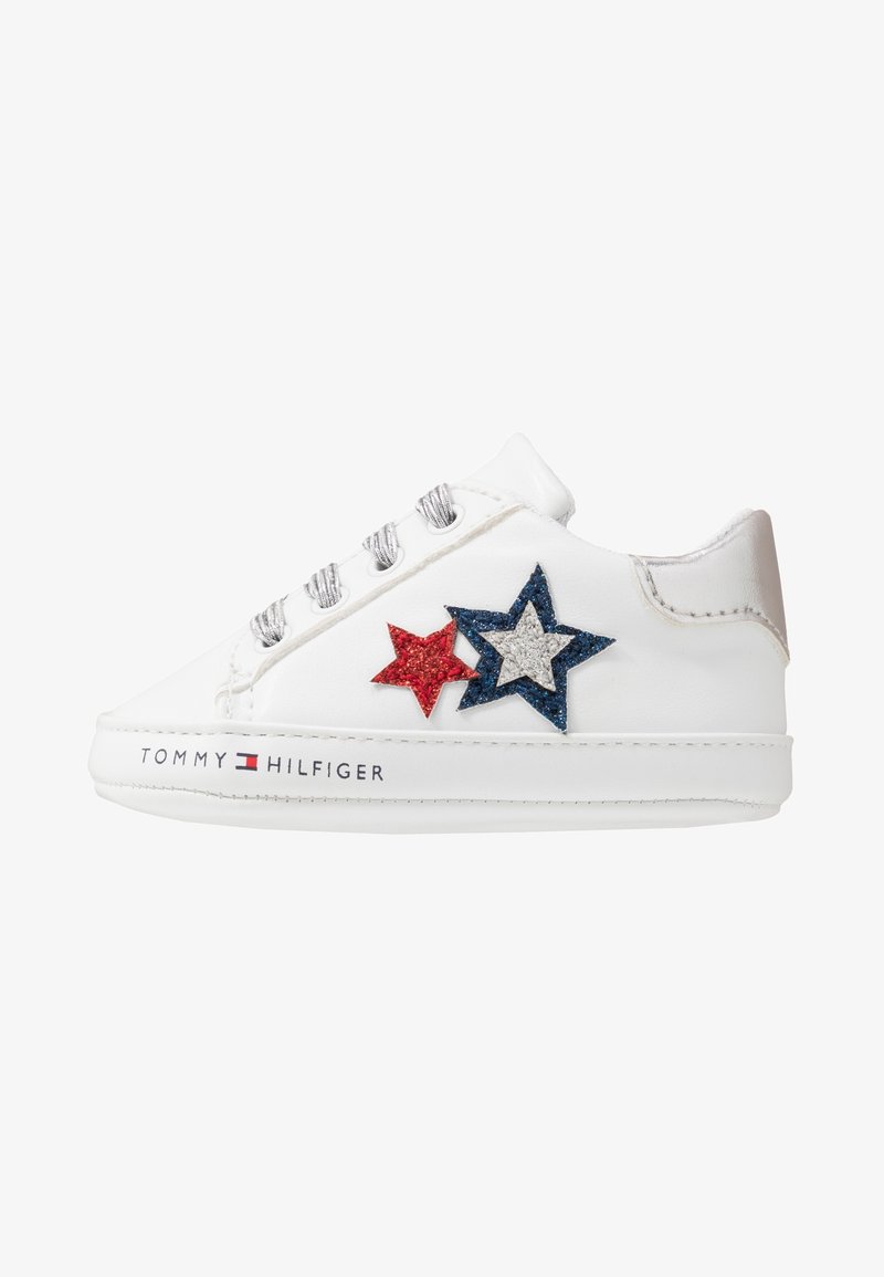 Baskets blanches basses avec lacets argentés, patchs étoiles pailletées rouges et bleues, et logo "Tommy Hilfiger" sur la semelle.