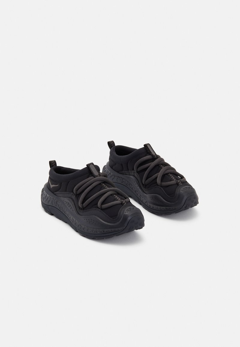Black athletic shoes with a textured rubber sole, padded fabric upper, elastic laces, and pull tabs at the heel for easy wear.