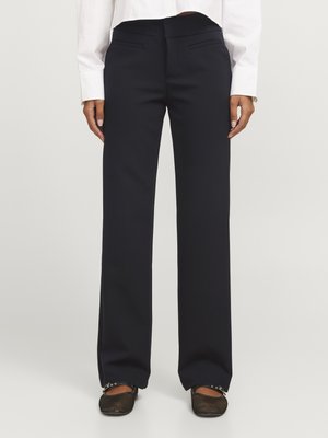 Pantalon large navy en tissu lisse, doté de poches latérales et d'une ceinture plate. Associé à des ballerines noires en mesh.
