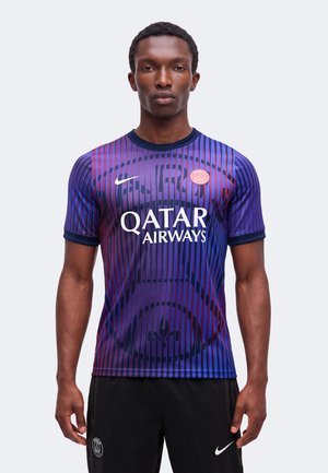 Muž nosiaci futbalový dres Paris Saint-Germain v modro-červených pruhovaných farbách s logom Qatar Airways, v kombinácii s čiernymi nohavicami značky Nike.