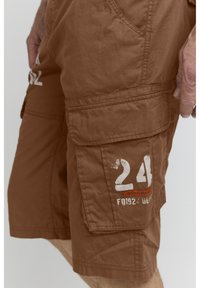 Barna cargo rövidnadrág texturált anyagból, nagy oldalsó zsebekkel, fehér és narancssárga "24" és "ORIGINAL BRAND" nyomattal.