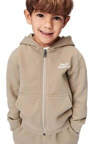 Beige zip-up hoodie med ett framsidesdesign, som har en känguruficka, ribbade mudd samt en mjuk textur. Idealisk för avslappnad klädsel.