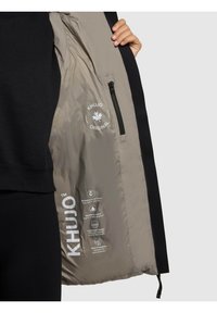 Must Black jacket, mille pehmea kangaga välimus ja kerge beež vooder. Sisaldab lukuga taskut ja prinditud hooldusjuhiseid voodril.