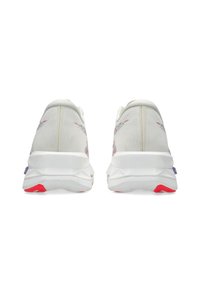Une paire de chaussures de sport blanches vue de l'arrière, dotées de semelles épaisses avec des accents rouges au niveau des talons.