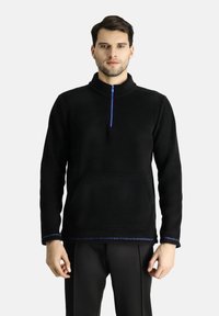 Sudadera de forro polar negra con un cuello alto, medio cierre frontal, bolsillo tipo pouch en la parte delantera y acentos de costura azul en el dobladillo y los puños.