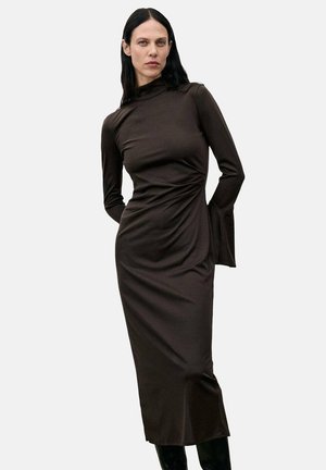 Vestido marrón de manga larga con un cuello alto, cuerpo ajustado y detalle drapeado en la cintura. Tela suave con un sutil brillo.