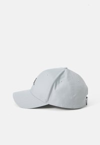 Grå stofhat med et struktureret design, buet skygge, ventilationshuller og et logo på siden. Glat tekstur, justerbar rem bagpå.