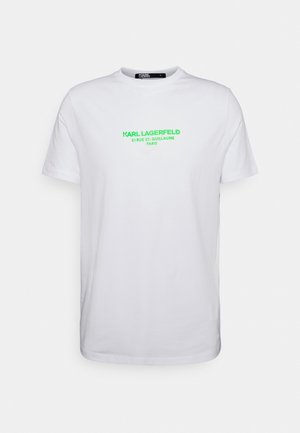 T-shirt en coton blanc avec un col rond et des manches courtes, affichant un texte en néon vert qui indique "KARL LAGERFELD 21 RUE ST-GUILLAUME PARIS."