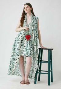 Kleita bez piedurknēm ar zaļu un krējuma krāsas rakstu, papildināta ar garu, plūstošu apmetni. Modelis tur sarkanu, pērlītēm izšūtu, zemeņu formas somiņu. Brūni čības.