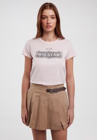 Rožinė medvilninė marškinė su užrašu "BIG STAR LEGENDINIAI MĖLYNI DŽINSAI". Sutampanti su šviesiai ruda plištine sijonu ir ruduo diržu su sidabriniu sagtimi.