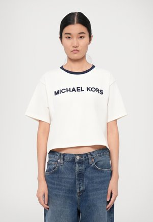 Vit kortärmad t-shirt med marinblå krage och "MICHAEL KORS" logotyp i mörkblått. Matchas med högmidjade blå denimjeans.