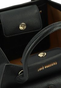 Borsa a mano in pelle nera con superficie texturizzata, accessori in oro, manici superiori e scomparto interno con una piccola tasca con chiusura a scatto.
