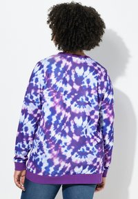 Felpa in tie-dye viola con una combinazione di motivi blu e bianchi, maniche lunghe e colletto e orlo a costine.
