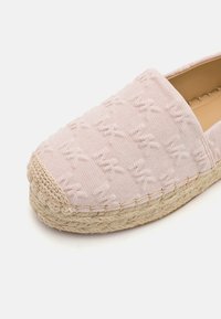 Espadrille rose clair avec motif brodé et semelle en jute tressée, vue en angle montrant le détail des coutures et la doublure intérieure beige.