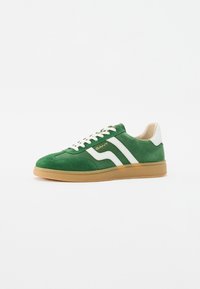 Adidași din suede verde cu accente albe și talpă din cauciuc dulce. Caracteristici includ un vârf rotund, design cu șireturi și o branding subtil.