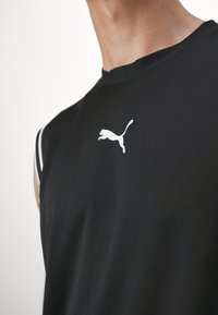 Μαύρο αμάνικο αθλητικό μπλουζάκι από υφασμένο ύφασμα, με λευκό λογότυπο Puma στο στήθος και διακριτές λευκές ρίγες στους ώμους.