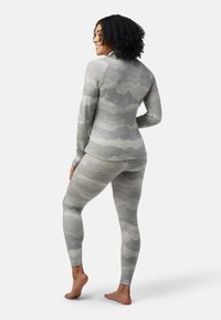 Grå mønstret termounderdel bestående af en langærmet bluse og leggings, med teksturerede bølgemønstre. Blødt, strækbart stof.