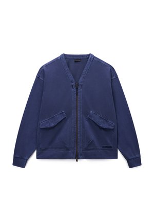 Veste zippée bleu marine en tissu doux, avec deux poches plaquées frontales, poignets côtelés et col en V. Simple et fonctionnelle.