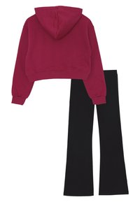 Vista posteriore di un hoodie rosso accorciato con maniche lunghe abbinato a pantaloni neri a gamba dritta su uno sfondo bianco.