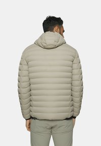 Beige gepolsterte Jacke mit Kapuze, ausgestattet mit horizontalen Nähten und einer glatten Textur. Die Rückansicht zeigt ein tailliertes Design mit elastischen Bündchen.