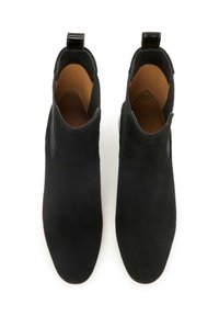 Botas de tobillo de ante negro con una textura suave, paneles laterales elásticos y una lengüeta en la parte trasera. Diseño de punta redonda y suela plana.