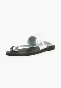 Black flat sandal with a white and silver strap design. Features a smooth leather texture and a minimal curved shape.