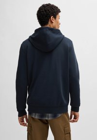 Navy blauwe hoodie gemaakt van een zachte katoenmix, met een ontspannen pasvorm en geribbelde manchetten, in een gelaagde look over een geruite shirt.