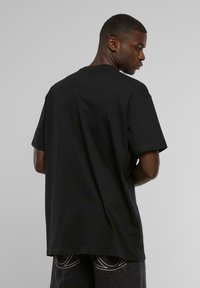 Sort bomulds T-shirt med korte ærmer, afslappet pasform og rund halsudskæring. Glat tekstur med minimal design og ingen synlige mønstre eller logoer.