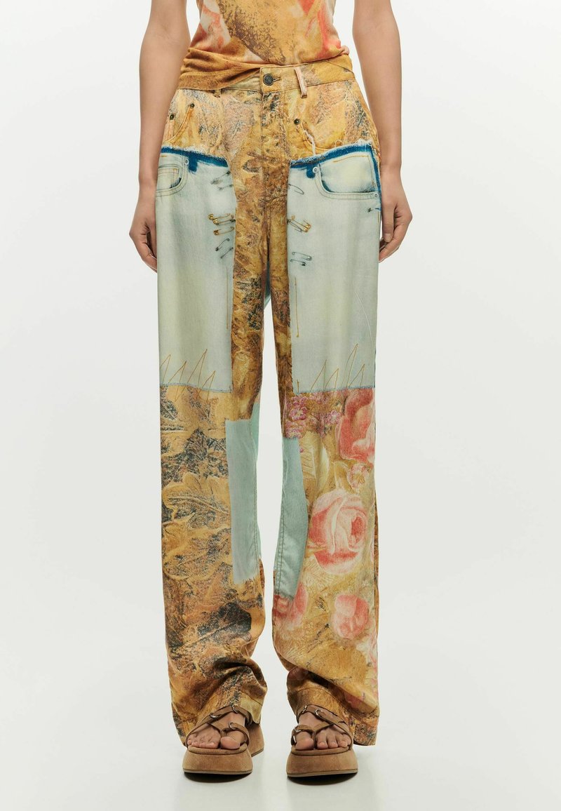 Pantalons à jambes larges avec imprimé floral mélangé et denim, portés avec des sandales plateformes à bout ouvert et un haut sans manches.