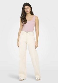 Pantalones de pierna ancha color beige claro combinados con una camiseta de tirantes rosa con textura acanalada y bordes festoneados. Textura suave y ajuste relajado.