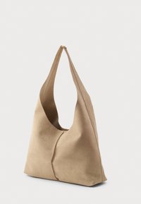 Borsa a spalla in suede beige con un corpo largo e curvo, una tracolla singola e una superficie liscia. Presenta cuciture minime per un aspetto pulito.