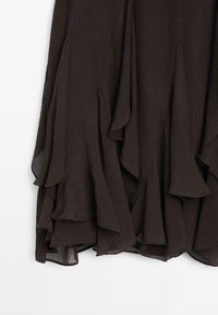 Donkerbruine, gelaagde rok met gerimpelde zoom, gemaakt van lichtgewicht stof. Heeft een geplooide textuur en zachte val.