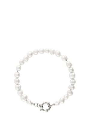 Pulsera con perlas blancas desiguales ensartadas, con un cierre circular de plata y pequeños eslabones para ajustar.