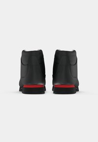 Ein Paar schwarze Wanderschuhe mit roten Akzenten, von hinten auf einem weißen Hintergrund gezeigt.
