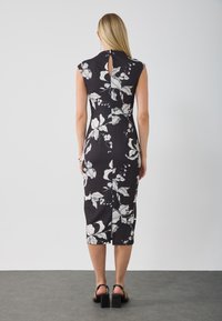 Rochie florală neagră cu modele albe de frunze, cu mâneci scurte, lungime până la genunchi, siluetă ajustată, cu o deschidere în formă de cheie la spate.